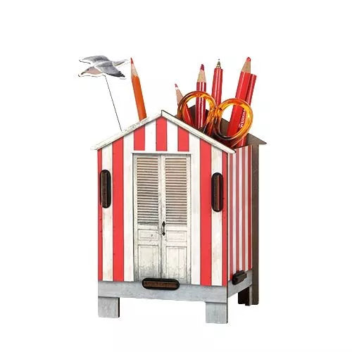 A decorative beach house pen pot with a seagull, placed on a desk next to a plant and a calculator.