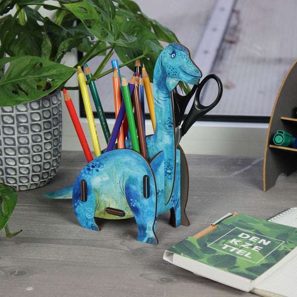 A Brachiosaurus-shaped pen pot with multiple compartments, filled with pencils and other stationery items. The pen pot is predominantly blue with green markings.