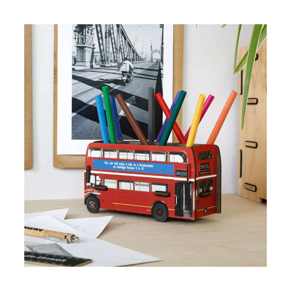 Red double-decker bus-shaped pencil holder with colorful pens on a desk.