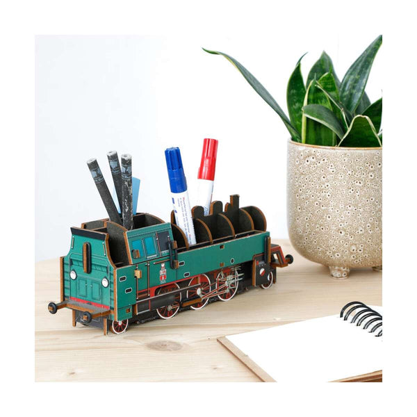Train-shaped pen holder with stationery items on a desk next to a plant