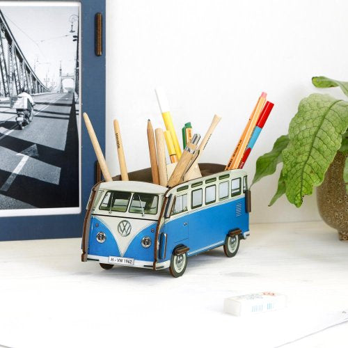 Blue and white Volkswagen van-shaped pencil holder with stationery items on a desk.