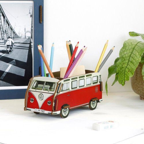 Red and white Volkswagen van-shaped pencil holder with pencils on a desk.
