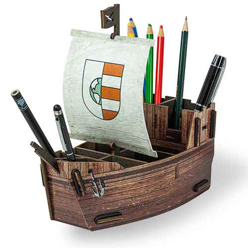 A wooden pirate ship pen pot filled with various pens and pencils, featuring a clip-together structure with compartments and an anchor on the bow.