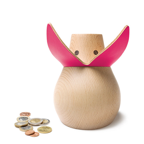 A beech wood pink leather money box in the shape of a lady's face with a pink leather flap, coins placed beside it for scale.